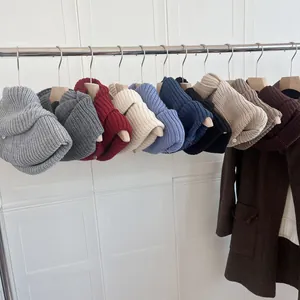 Detail of thick knitted pullover snoods in various colors hanging on wooden hangers