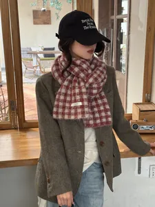 Close-up of a cozy red and white checkered knit scarf on a model in a cafe setting