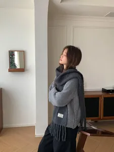 Side view of model wearing a grey wool tassel scarf with a MICKEY RABBIT label detail