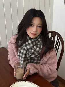 Close-up of a stylish checkered knit scarf worn by a woman in a cozy setting