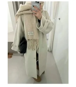 Detailed visual of beige UNDERSON thick wool scarf featuring fringe and brand logo tag