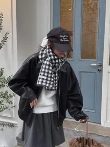 Model wearing a black and white checkered knit scarf with a leather jacket outfit