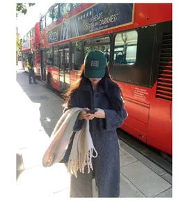 Thick beige wool scarf with tassels held by a model in an atmospheric London street scene