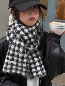 Detailed view of a black and white checkered knitted scarf paired with a black leather jacket