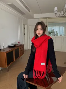 Fashionable red wool blend fringed shawl worn by an Asian model in an indoor setting.