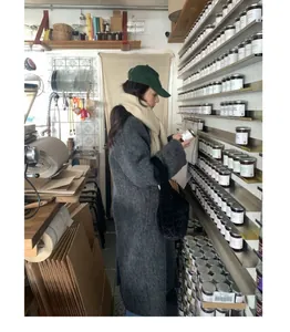Detailed lifestyle shot of a warm beige wool scarf styled with a grey winter coat