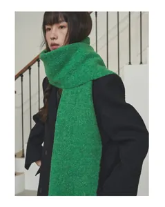 Stylish Asian woman wearing a cozy bright green wool scarf and black coat on stairs.