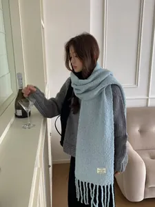 Close-up of a cozy light blue wool scarf with long tassels in a stylish minimalist room