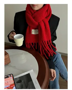 Close-up of thick red wool scarf featuring UNDERSON brand label and soft fringe detail