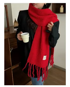 Detail view of a thick red wool scarf with tassels worn on a black blazer jacket