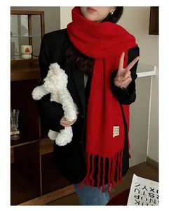 Detailed view of a thick red wool scarf with fringes worn with a black blazer.