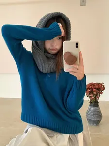 Lifestyle shot showing a gray chunky knitted hooded scarf paired with a blue sweater