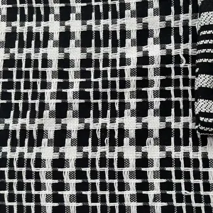 Macro view of black and white woven cotton linen fabric with classic houndstooth pattern.