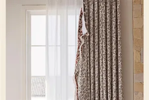 Vista dettagliata della tenda in ciniglia jacquard ciliegia con decorazione a pompon.