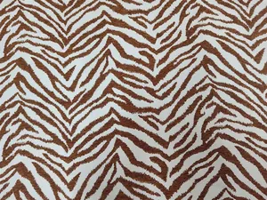 Primo piano dettagliato del tessuto ciniglia jacquard con motivo zebrato marrone e bianco.