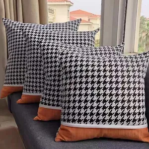 Modern houndstooth and orange chenille patchwork cushion covers on stylish grey sofa