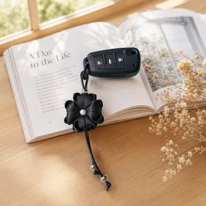 Close-up of black satin clover flower keychain with pearl detail on an open book