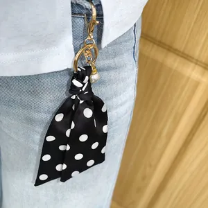 Detailweergave van een zwart-wit gestippelde sjaalsleutelhanger met een parel.