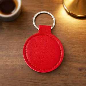 Premium minimalist red circular PU leather keychain with silver ring on a rustic wooden desk