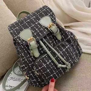 Vintage tweed backpack detail showcasing textured fabric, green leather straps and metal buckles.