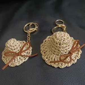 Porte-clés mini chapeau de paille tissé main avec nœud marron et anneau doré.