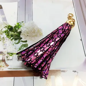 Detail view of a purple holographic leather tassel pendant with elegant black mesh overlay.