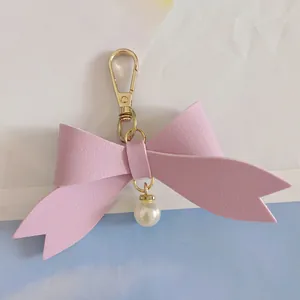 Detailed view of a cute pink PU leather bow keychain featuring a delicate pearl pendant