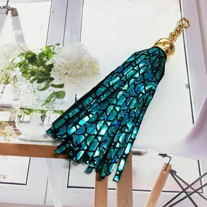 Detailed view of a metallic turquoise leather tassel keychain with golden metal ring and cap