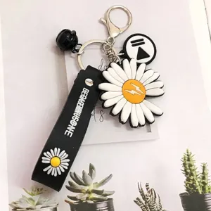 Close-up detail of the stylized daisy charm and branded rubber strap on this Korean style keychain
