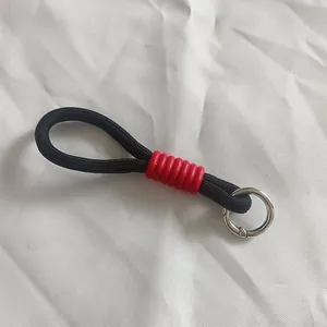 Primer plano de cordón trenzado negro con funda roja y anillo de resorte metálico