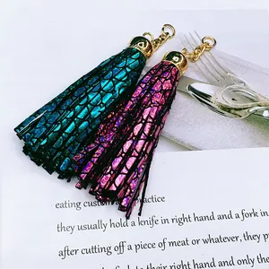Close-up of metallic patterned leather tassels with gold-tone hardware on white paper