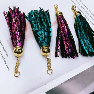 Macro view of metallic snake-skin leather tassels with gold metal findings for bag charms.