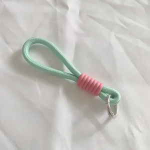Primer plano del cordón trenzado verde menta con funda rosa y hebilla de resorte plata.