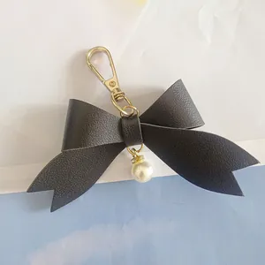 Detailed view of black textured PU leather bow keychain with elegant pearl charm