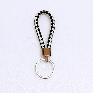 Close-up detail of black and white woven leather cord keychain with silver ring
