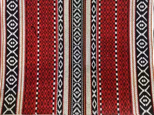 Primo piano di tessuto jacquard intrecciato in stile etnico con motivi geometrici rossi e neri