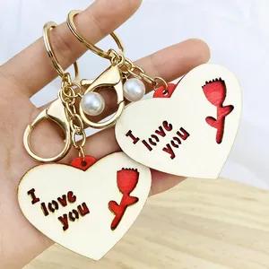 Détail d'un porte-clés en bois en forme de cœur avec découpe I love you et une perle