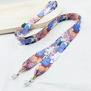 Détail d'un ruban de soie imprimé floral avec d'élégantes perles blanches.