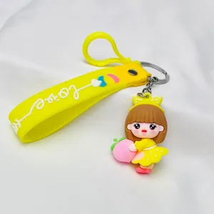 Close-up detail of a cute yellow silicone keychain featuring a cartoon girl holding a pink peach
