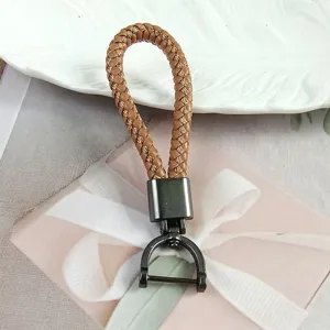 Detail view of a woven tan leather keychain with a gunmetal horseshoe D-ring clasp.