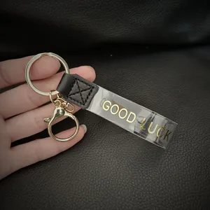 Λεπτομέρεια μάκρο του χρυσού 'GOOD LUCK' κειμένου σε διαφανές λουράκι για μπρελόκ τσάντας