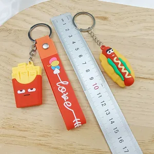 Detail view of cartoon french fries and hot dog keychains with a ruler for scale