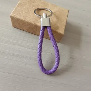 Detalle de un llavero de cuero trenzado morado con un anillo plano de metal plateado
