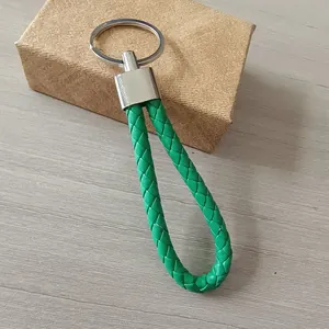 Primer plano de un llavero de cuero trenzado verde con un anillo de metal plateado pulido