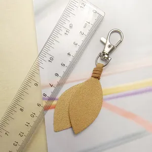Detail of camel suede leaf keychain next to a ruler showing its size and soft texture.