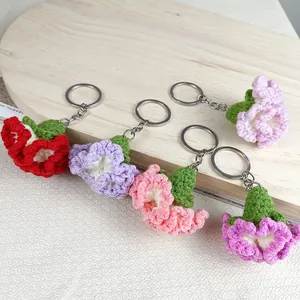 Set van handgehaakte anjer sleutelhangers in diverse pastelkleuren op een licht houten dienblad