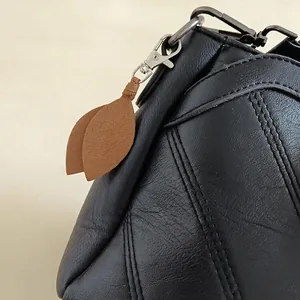 Fashionable brown faux suede leaf keychain charm on a black textured leather bag