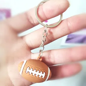 Mini llavero creativo de fútbol americano en PVC 3D sostenido en la mano de una persona