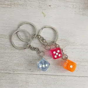 Close-up detail of colorful translucent acrylic dice keychains in blue pink and orange
