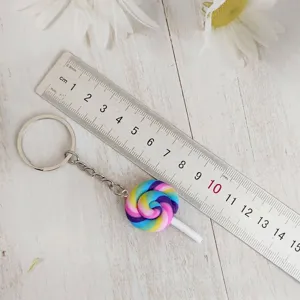 Detail shot of colorful rainbow lollipop keychain next to a ruler for size scale